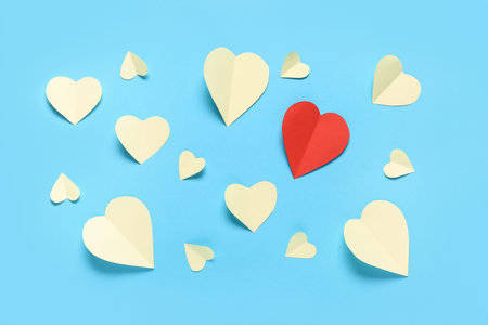 Red paper heart among yellow ones on color background. Valentine's Day celebration