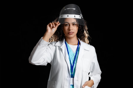 Female African-American medical intern in protective mask on black backgroundの写真素材
