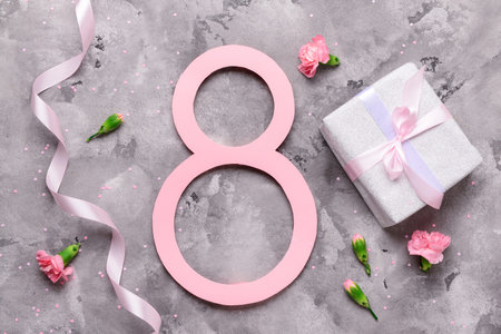 Figure 8 with gift box, ribbon and beautiful flowers on gray background. International Women's Day