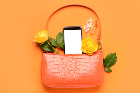 Composition with stylish female handbag, mobile phone and rose flowers on color backgroundの写真素材
