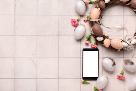 Composition with modern mobile phone, Easter decor and flowers on light tile background