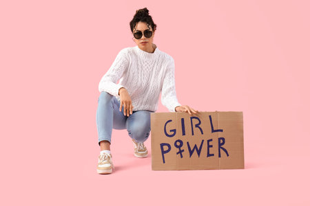 Beautiful young African-American woman holding paper with text GIRL POWER on pink background. Women history monthの写真素材