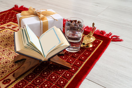 Koran with gift, water, dates and Aladdin lamp on praying mat, closeup. Ramadan celebrationの写真素材