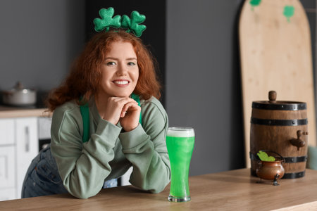 Young woman with beer in kitchen. St. Patrick's Day celebrationの写真素材