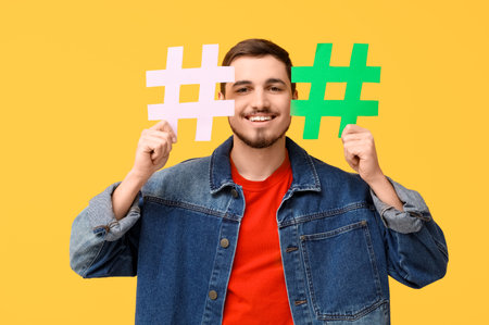 Handsome young man with hashtag signs on yellow backgroundの写真素材