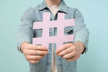 Man with hashtag sign on blue background, closeup