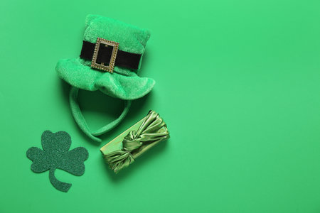 Gift box with leprechaun hat and paper clover on green background. St. Patrick's Day celebrationの写真素材
