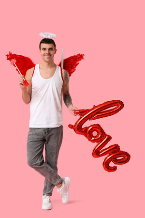 Young man dressed as Cupid with arrow and word LOVE made of balloons on pink background. Valentine's Day celebrationの写真素材