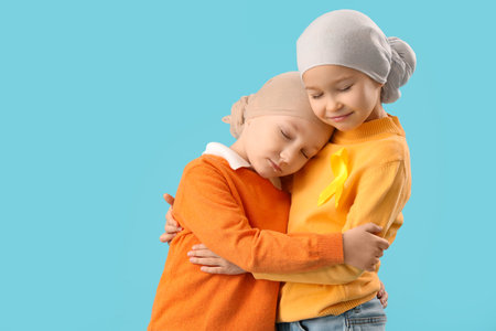 Cute little children after chemotherapy with yellow ribbon on blue background. Childhood cancer awareness conceptの写真素材