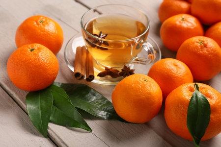 Sweet mandarins, star anise, cinnamon and cup of tea on gray wooden backgroundの写真素材