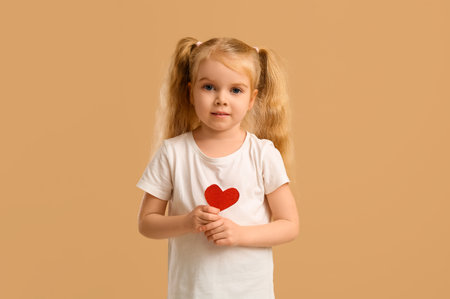 Cute little girl with heart on beige background. Valentine's Day celebrationの写真素材