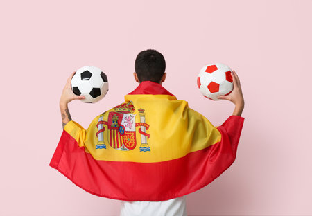 Young man with soccer balls and flag of Spain on pink backgroundの写真素材