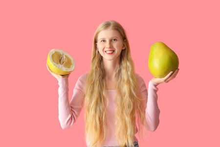 Young woman with pomelo on pink backgroundの写真素材
