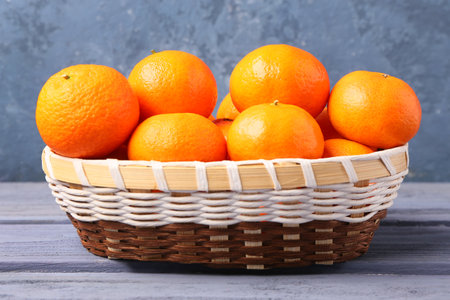 Basket with tasty tangerines on gray wooden tableの写真素材