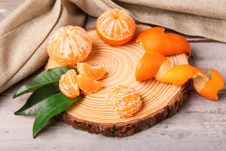 Board with tasty tangerines and leaves on gray wooden tableの写真素材
