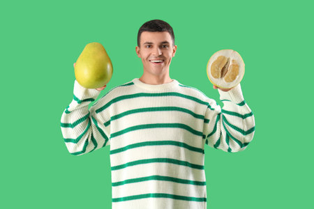 Young man with pomelo on green background