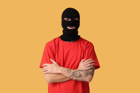 Handsome young man in balaclava on yellow backgroundの写真素材
