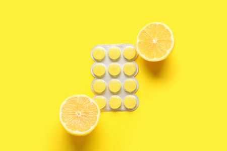 Pills for sore throat with lemon on yellow backgroundの写真素材