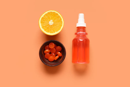 Pills for sore throat with cough spray and orange on color backgroundの写真素材