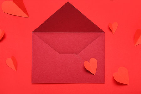 Composition with envelope and paper hearts on red background. Valentine's Day celebration