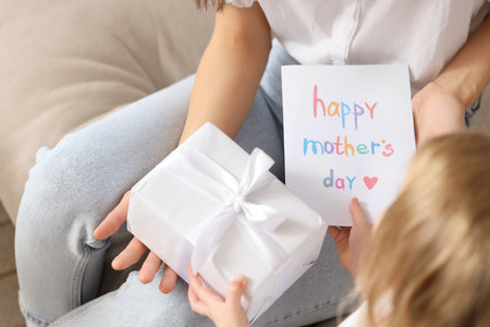 Little girl congratulating her mom with greeting card and gift box at home,closeup. Mother's Day celebrationの写真素材