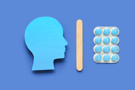 Paper human head with pills for sore throat and tongue depressor on blue background