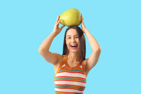 Pretty young woman with ripe pomelo on blue background