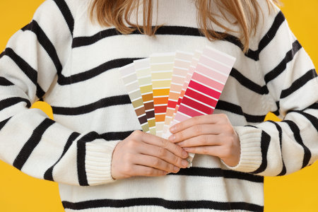 Woman with color palettes on yellow background, closeup