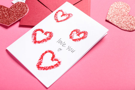 Greeting card with text LOVE YOU, envelope and hearts on pink background, closeup. Valentine's Day...