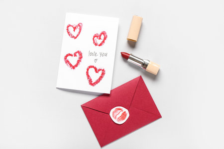 Greeting card, envelope and lipstick on gray background. Valentine's Day celebration
