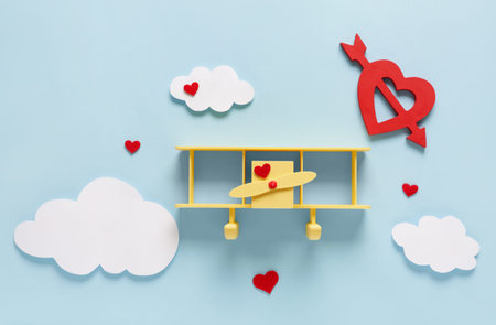 Toy airplane with paper hearts and clouds on blue background. Valentine's Day celebration