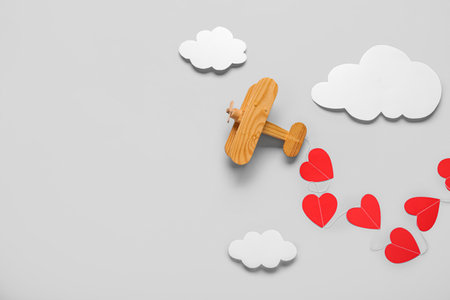 Wooden airplane with paper hearts and clouds on light background. Valentine's Day celebrationの写真素材