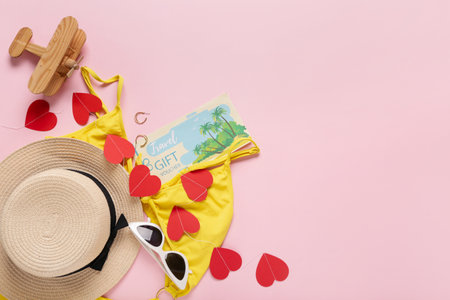 Travel gift voucher with beach accessories and hearts on pink background. Valentine's Day celebrationの写真素材