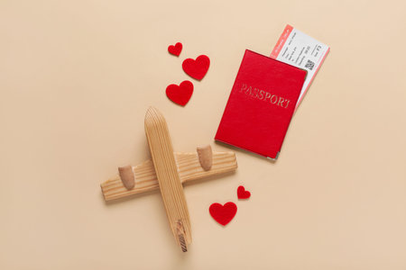 Passport with ticket, hearts and wooden airplane on beige background. Valentine's Day celebration