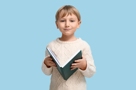 Little boy reading book on blue backgroundの写真素材