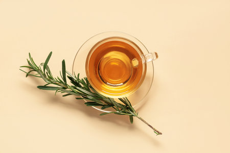 Glass cup of hot rosemary tea on beige backgroundの写真素材