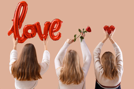 Women holding word LOVE made from balloons, rose and heart on beige background, back view. Valentine's Day celebrationの写真素材