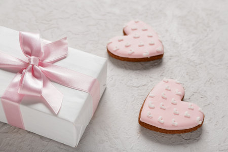 Tasty heart shaped cookies with gift box on white grunge background. Valentine's Day celebration