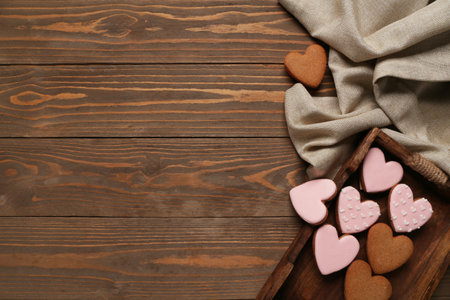 Tray with tasty heart shaped cookies and tablecloth on wooden background. Valentine's Day celebrationの写真素材