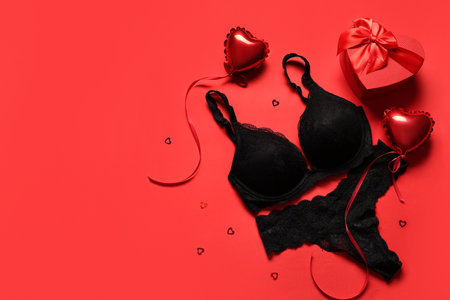 Composition with sexy lingerie, gift box and heart-shaped balloons on red background. Valentine's Day celebrationの写真素材
