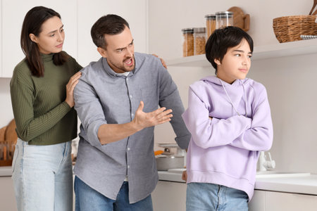 Teenage boy with his arguing parents in kitchen. Family problem conceptの写真素材