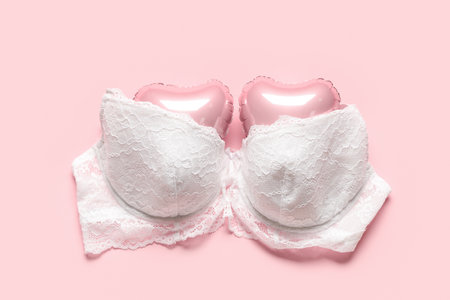 White female bra with heart-shaped balloons on pink background. Valentine's Day celebrationの写真素材