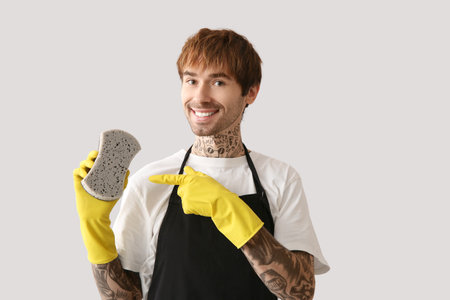 Young tattooed man with sponge on light backgroundの写真素材