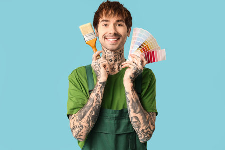 Happy male painter with different palette samples and paint brush on color backgroundの写真素材