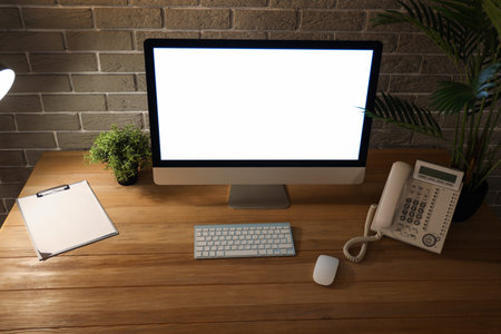 Blank computer monitor with telephone on table in office at night