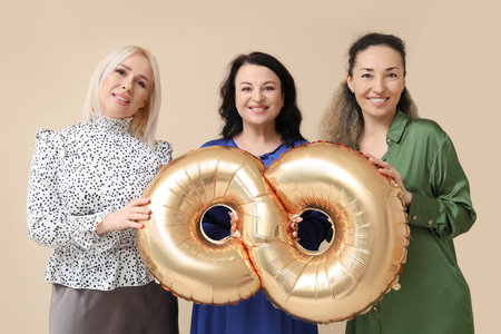 Mature women with golden air balloon in shape of figure 8 on beige background. International Women's...