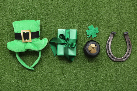 Pot with golden coins, horseshoe and leprechaun hat on grass. St. Patrick's Day celebration