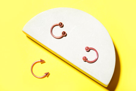 Plaster podium and circular barbells for piercing on yellow backgroundの写真素材