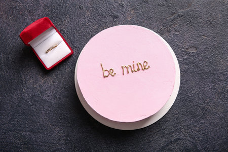 Pink bento cake and engagement ring on black grunge background. Valentine's Day celebrationの写真素材