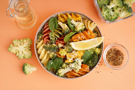 Delicious fusilli pasta with broccoli in bowl and spices on beige backgroundの写真素材